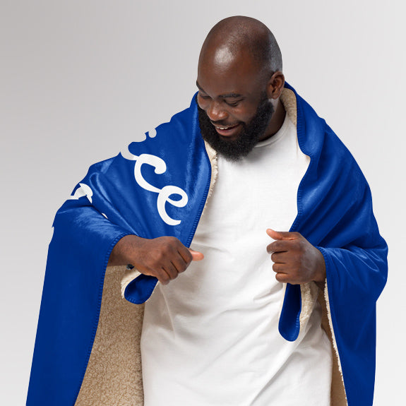 Man opening the Rotary sherpa blanket to reveal sherpa lining and outer message design.