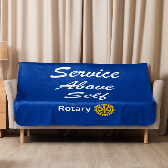 Navy blue Rotary sherpa blanket with “Service Above Self” script and Masterbrand logo fully displayed on a sofa.