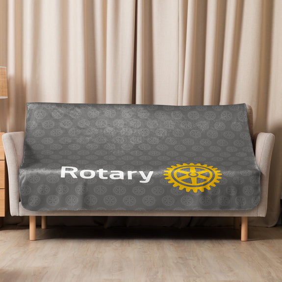 Rotary sherpa blanket fully spread over a sofa, clearly showing the simplified Masterbrand logo and repeating Rotary emblem design.