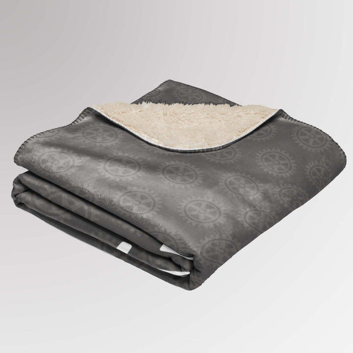 Neatly folded grey Rotary sherpa blanket with visible soft sherpa lining and corner of the logo pattern showing.