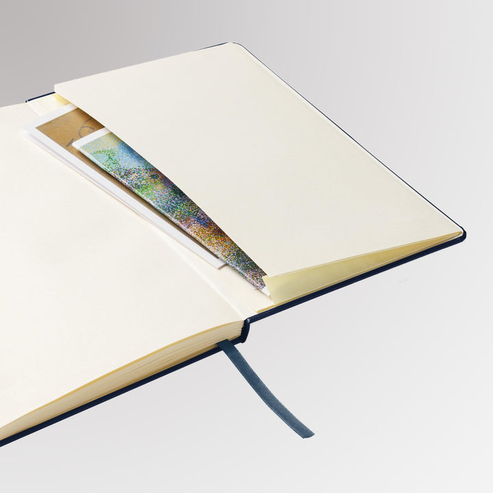 Back interior pocket of the notebook holding cards, showing ribbon marker and cream page edges.