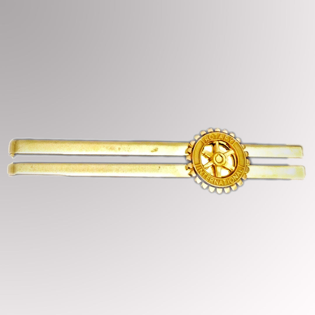 A gold-plated tie clip featuring Rotary International's Mark of Excellence.