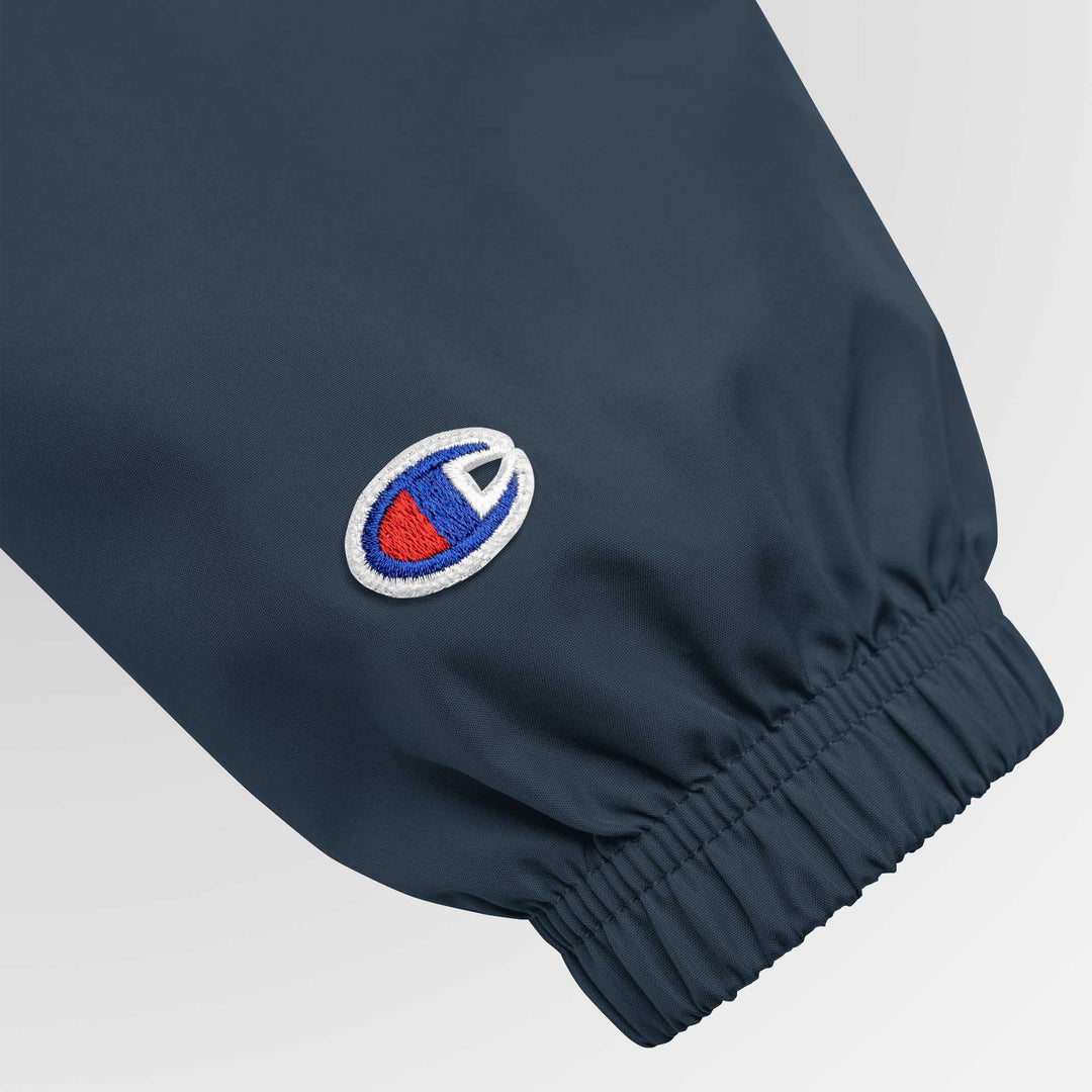 Close-up of the left sleeve showcasing the embroidered Champion “C” logo above the elastic cuff.