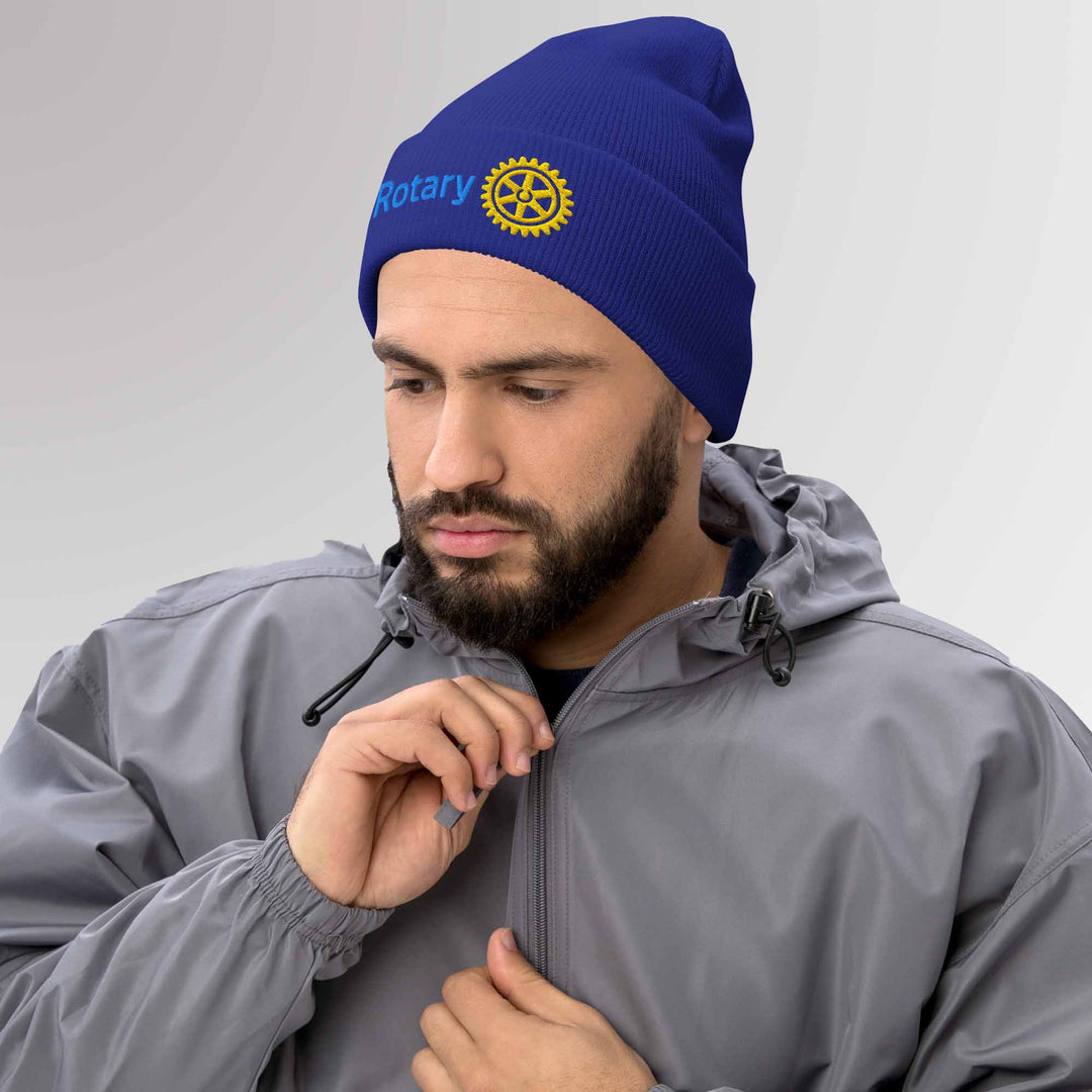 Male model showcasing a high-quality blue cuffed beanie featuring the Rotary International Master Brand logo embroidered, ideal for casual and Rotary events