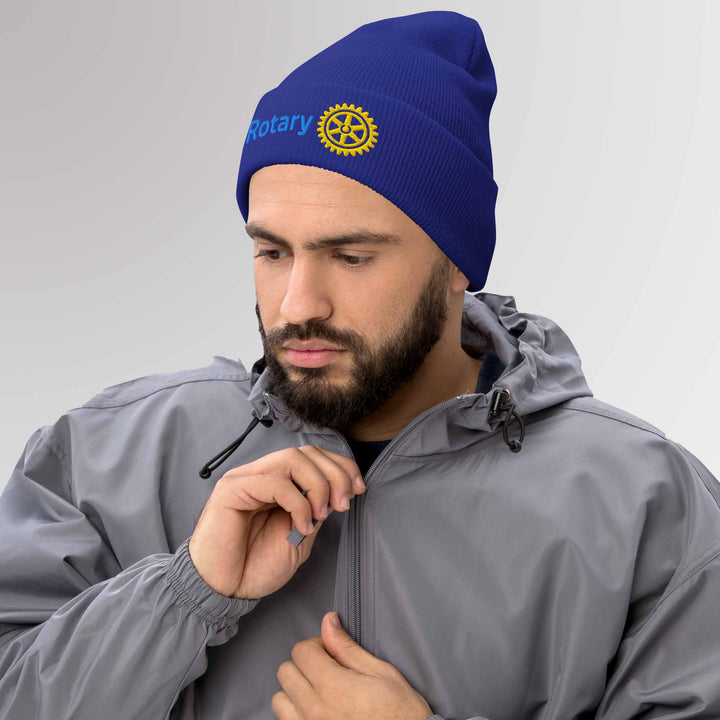 Male model showcasing a high-quality blue cuffed beanie featuring the Rotary International Master Brand logo embroidered, ideal for casual and Rotary events