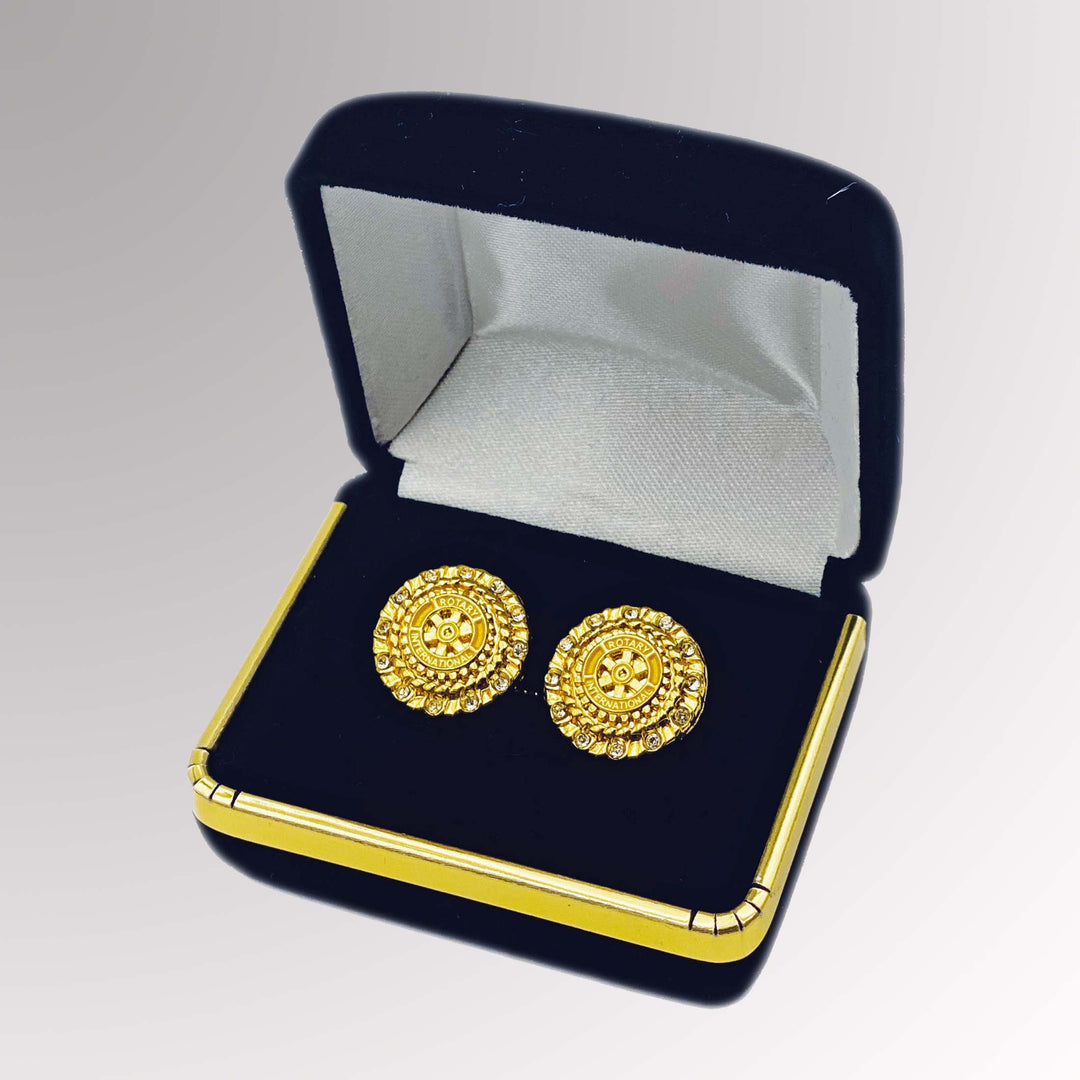 A pair of gold-plated Rotary Cuff Links with white imitation stones featuring Rotary International's Mark of Excellence logo.