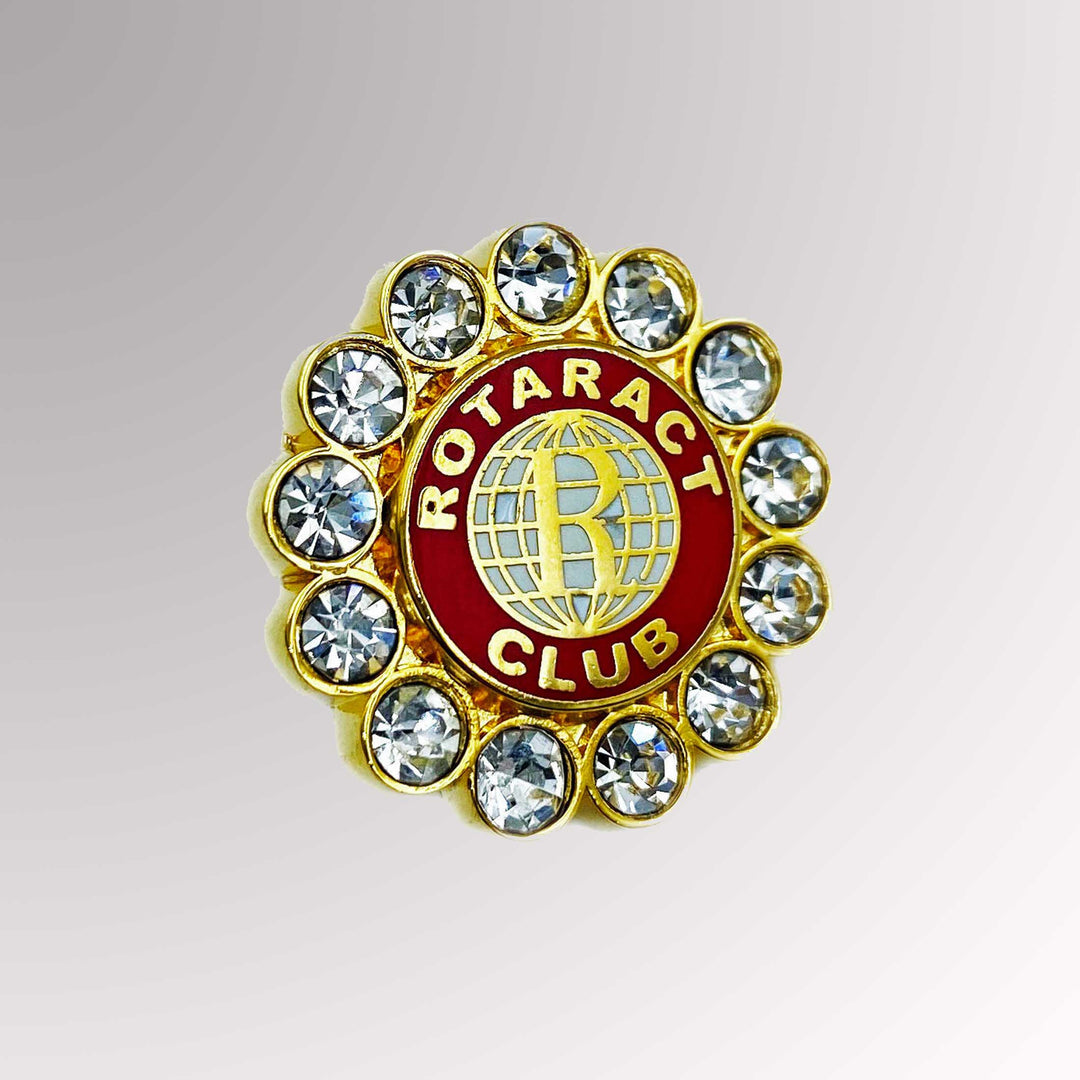 A gold-plated Rotaract Member Pin featuring the old Rotaract logo surrounded by white imitation stones.