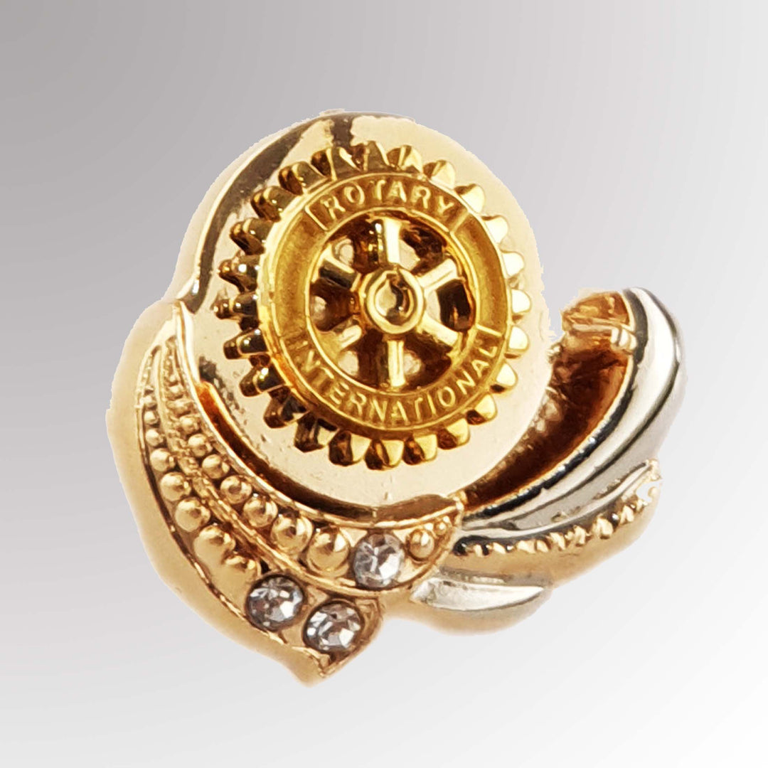 A polished metal Fancy Rotary Pin featuring Rotary International's Mark of Excellence logo with white imitation stones.