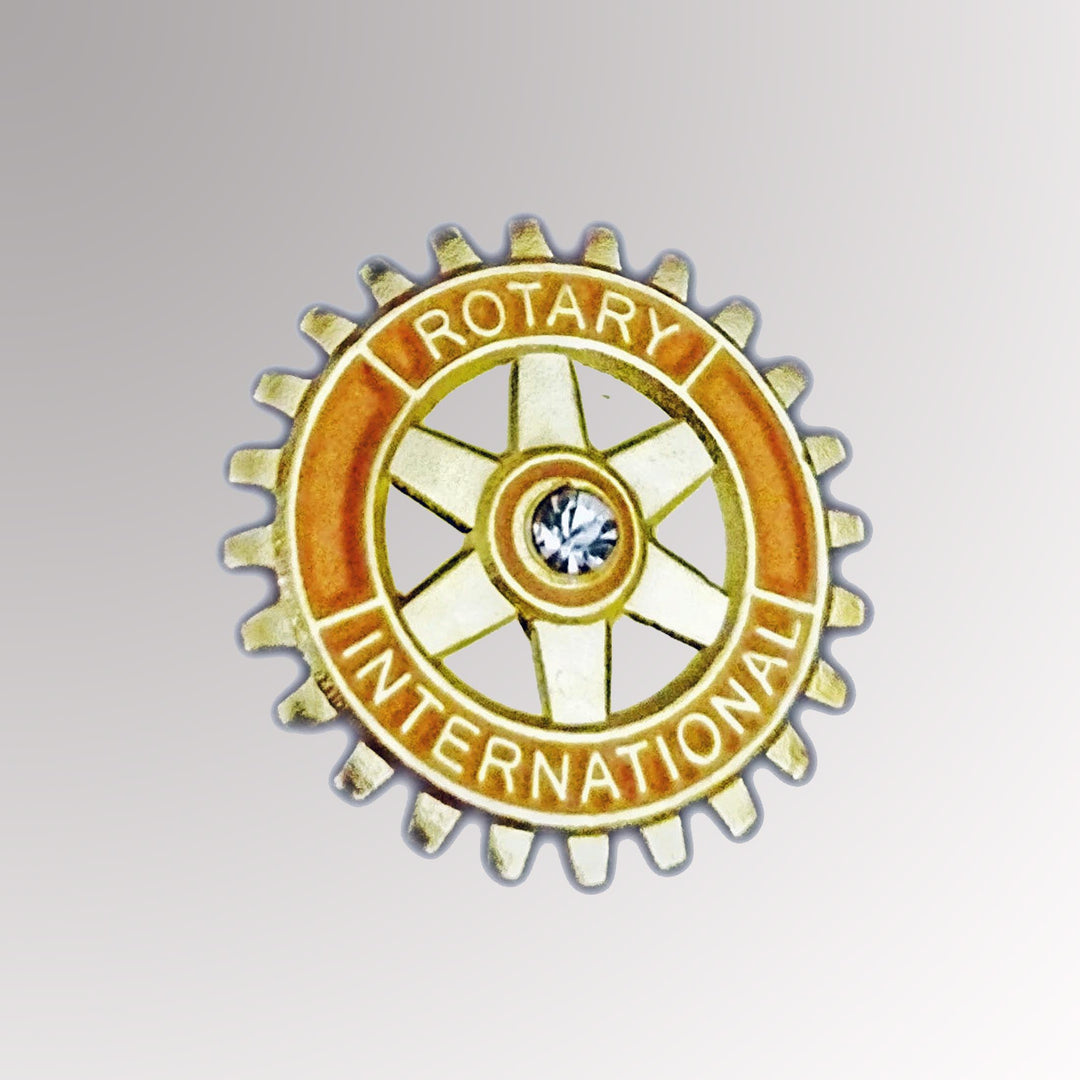 A gold-plated Rotary member pin featuring the Mark of Excellence and a white imitation stone in the center.