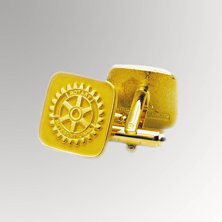 A pair of gold-plated Rotary Cuff Links with a matte background featuring Rotary International's Mark of Excellence logo.