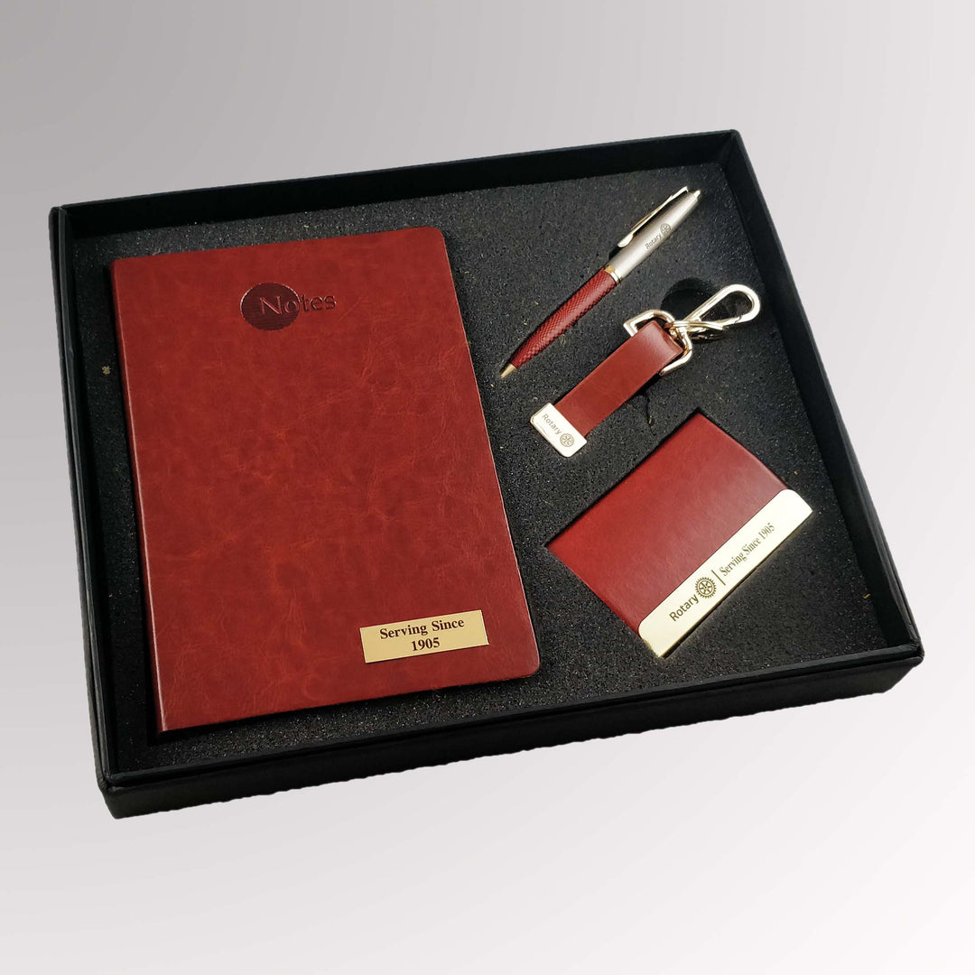 A gift set including an A5 notebook, ballpoint pen, card holder, and key chain, all featuring Rotary International's Master Brand logo.