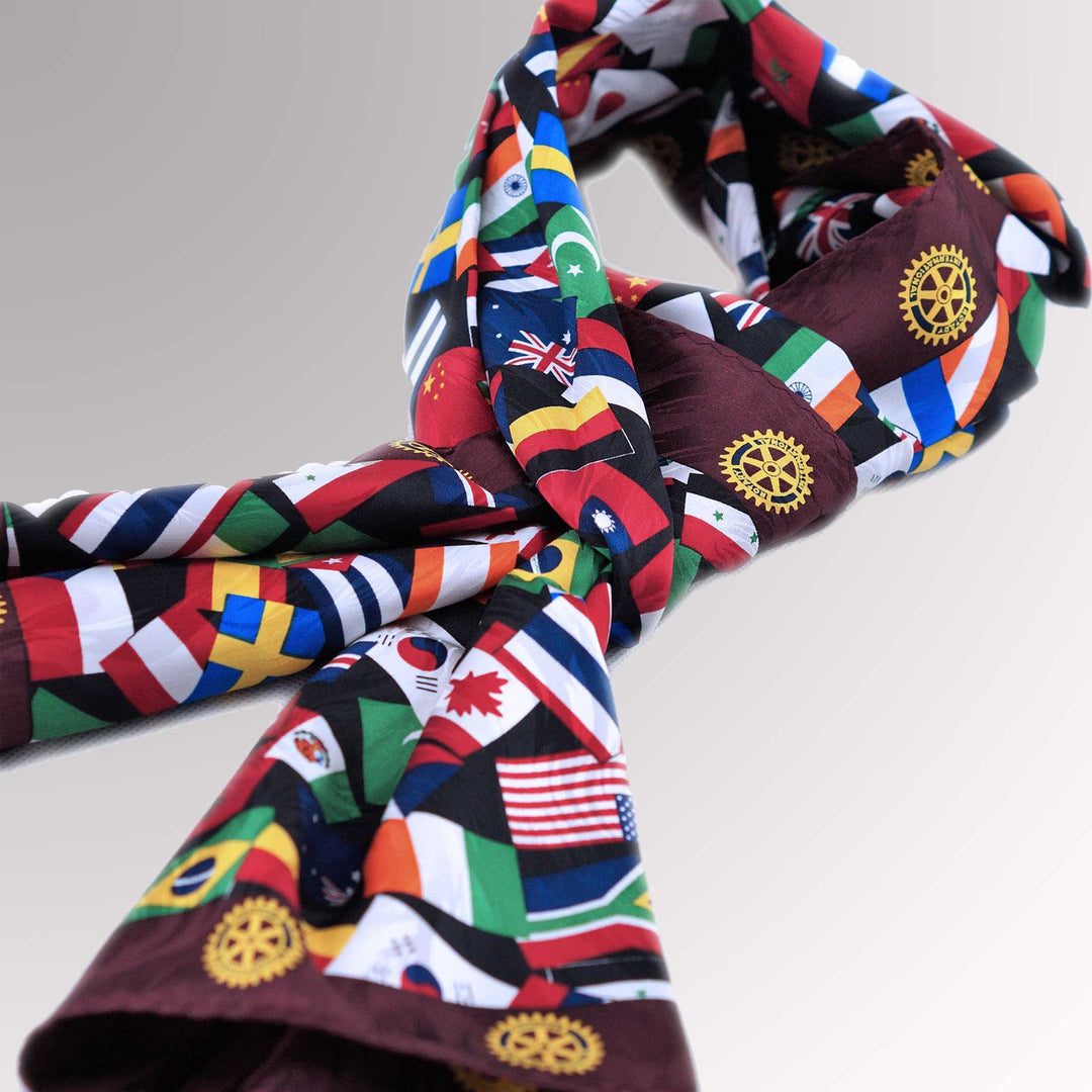 A high-quality silk scarf with a maroon border, featuring multi-national flags and the Rotary Mark of Excellence logo.